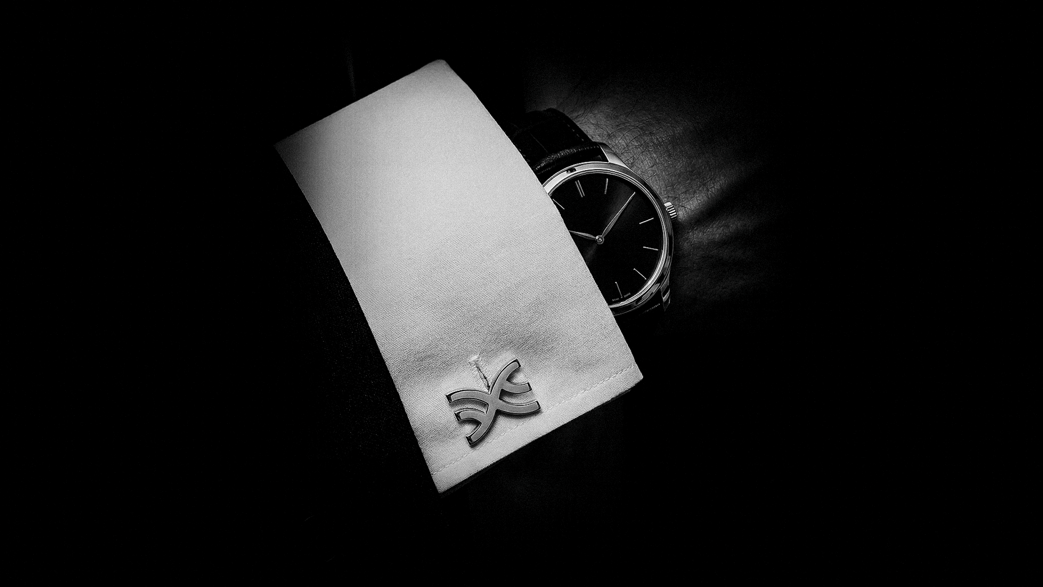 LXIX cufflink detail beside a wristwatch