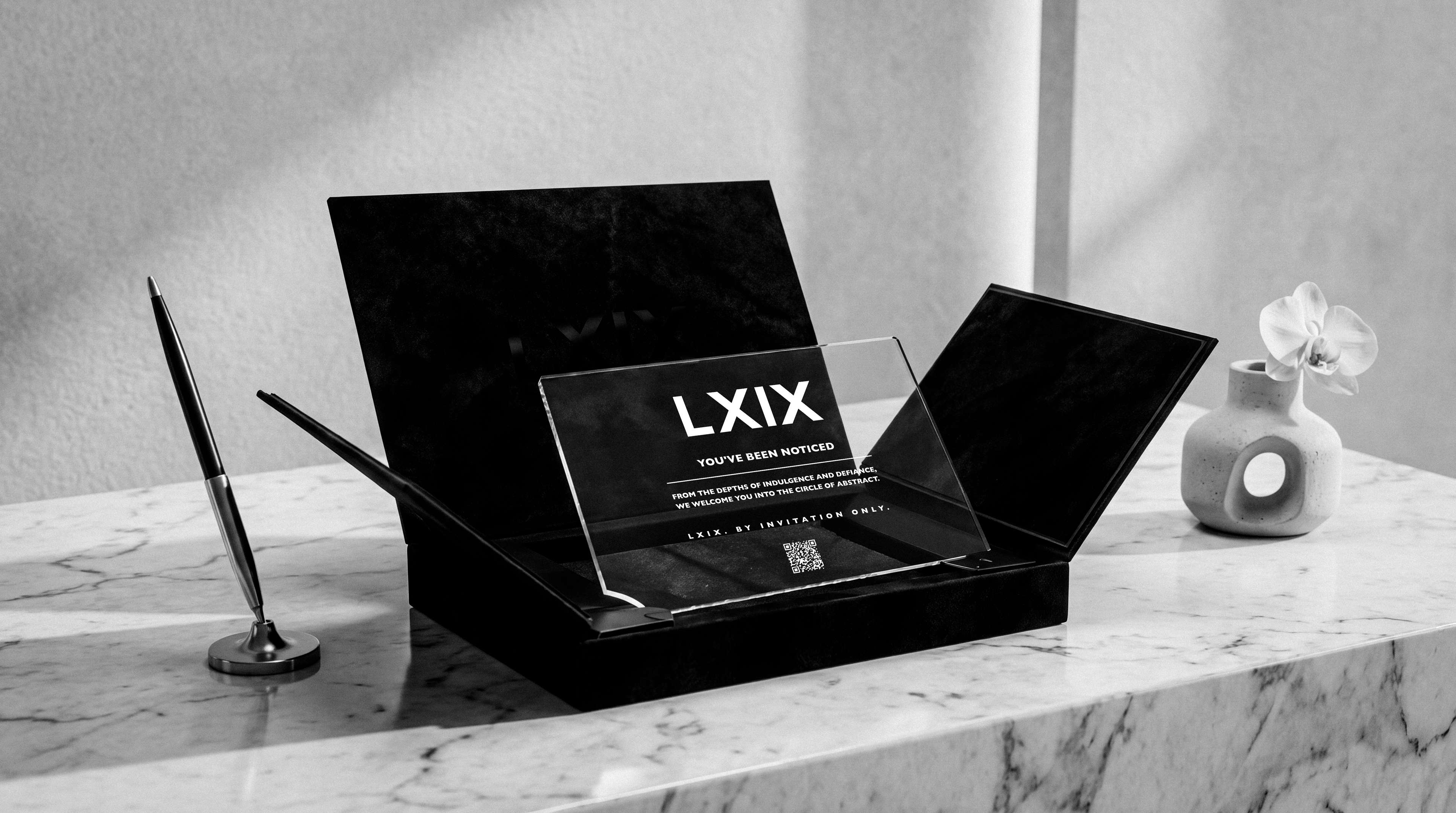 An LXIX invitation card reading 'You've been noticed', staged on marble
