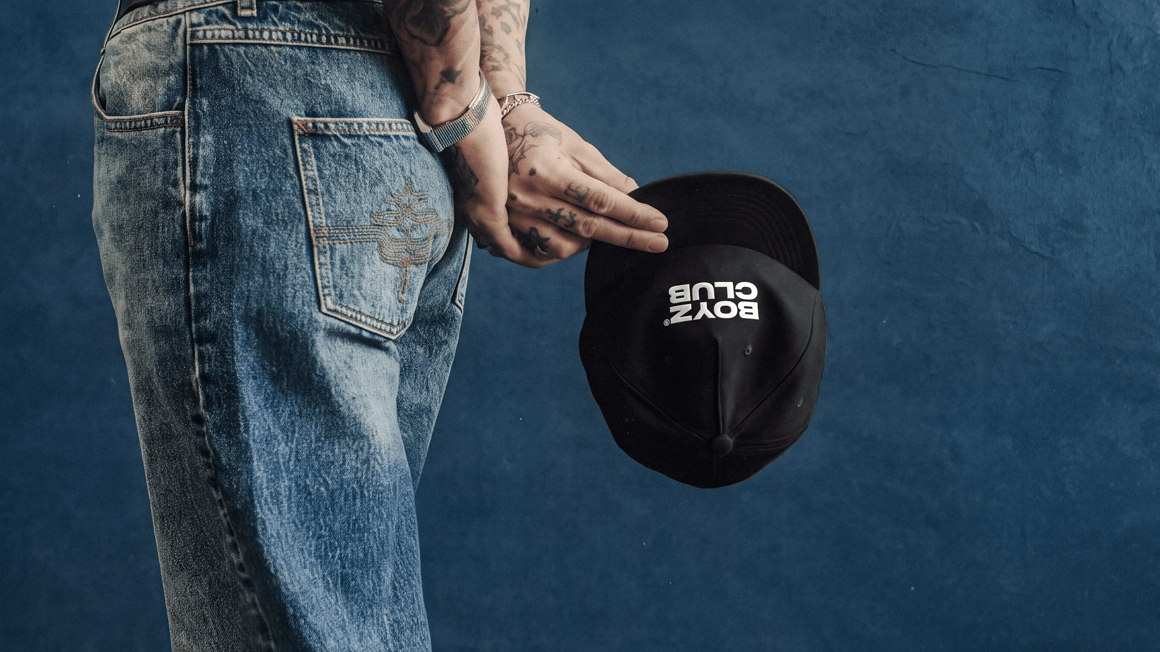 BoyzClub cap held against denim