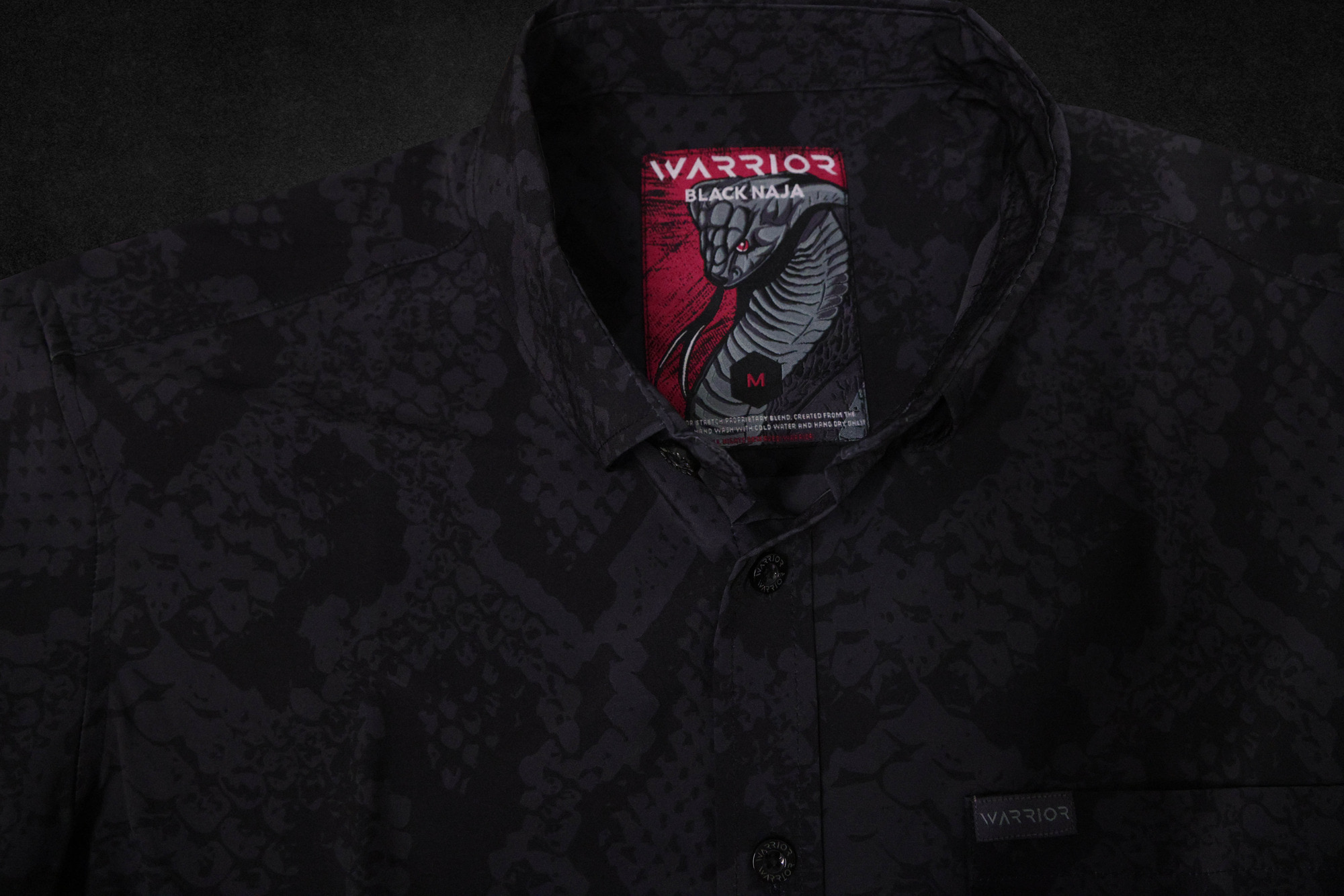 Black Naja tag sewn into a dark snake-print garment collar
